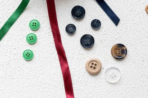Cufflinks, Sewing Materials, Colorful Threads, and Scissors on a White Surface Foto stock