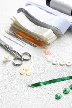 Cufflinks, Sewing Materials, Colorful Threads, and Scissors on a White Surface Foto stock