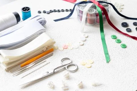 Cufflinks, Sewing Materials, Colorful Threads, and Scissors on a White Surface Foto stock