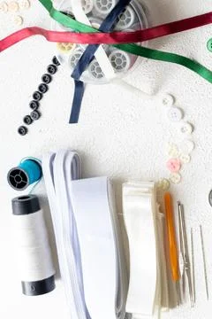 Cufflinks, Sewing Materials, Colorful Threads, and Scissors on a White Surface Foto stock