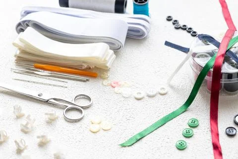 Cufflinks, Sewing Materials, Colorful Threads, and Scissors on a White Surface Foto stock