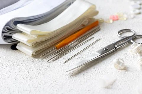 Cufflinks, Sewing Materials, Colorful Threads, and Scissors on a White Surface Foto stock