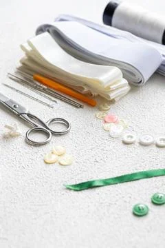 Cufflinks, Sewing Materials, Colorful Threads, and Scissors on a White Surface Foto stock