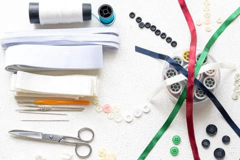 Cufflinks, Sewing Materials, Colorful Threads, and Scissors on a White Surface Foto stock