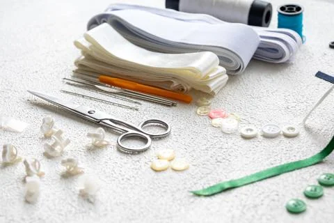 Cufflinks, Sewing Materials, Colorful Threads, and Scissors on a White Surface Foto stock