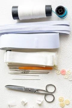Cufflinks, Sewing Materials, Colorful Threads, and Scissors on a White Surface Foto stock