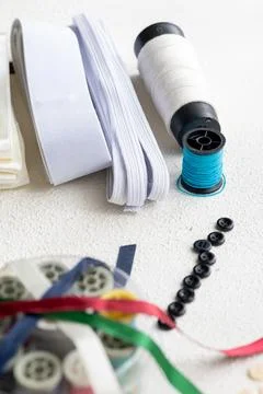 Cufflinks, Sewing Materials, Colorful Threads, and Scissors on a White Surface Foto stock