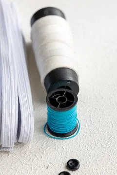 Cufflinks, Sewing Materials, Colorful Threads, and Scissors on a White Surface Foto stock