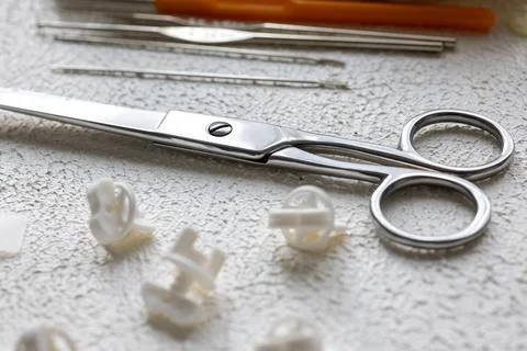 Cufflinks, Sewing Materials, Colorful Threads, and Scissors on a White Surface Foto stock