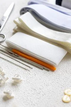 Cufflinks, Sewing Materials, Colorful Threads, and Scissors on a White Surface Foto stock