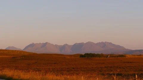 Cuillin Hills seen from far at sunset with a car crossing in front of the camera Stock Footage 97524186