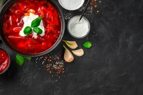 Culinary background with beetroot soup, sour cream and basil on a black concr Stock Photos