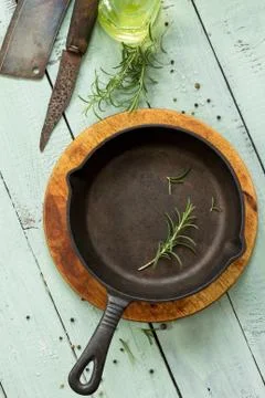 Culinary background. Empty cast-iron frying pan, fresh rosemary, olive oil. Stock Photos