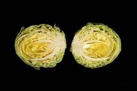 Culinary background. Halfs of cut white cabbage on black background. Stock Photos