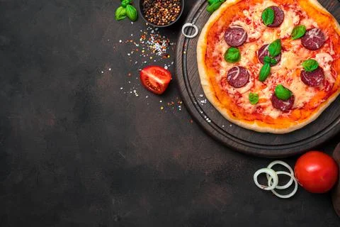 Culinary background with pepperoni pizza on a brown background with tomatoes and Stock Photos