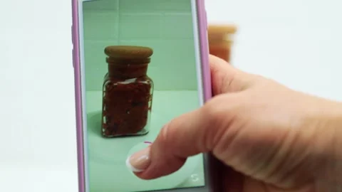 A culinary blogger films on a smartphone how a can of adjika rotates Stock Footage 252838375