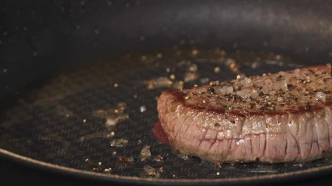 Culinary - Chef turns over a piece of beef steak in hot frying pan Stock Footage 105173014