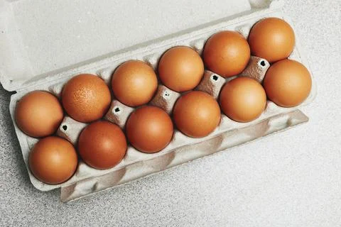 Culinary class in a kitchen. A dozen of tinted brown chicken eggs in an open  Stock Photos