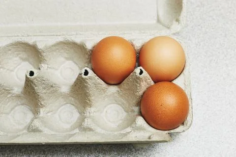 Culinary class in a kitchen. Three tinted brown chicken eggs in an open carto Stock Photos
