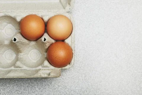 Culinary class in a kitchen. Three tinted brown chicken eggs in an open carto Stock Photos