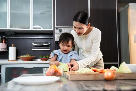 Culinary Collaboration: A tender moment unfolds as a mother guides her daug.. Stock Photos