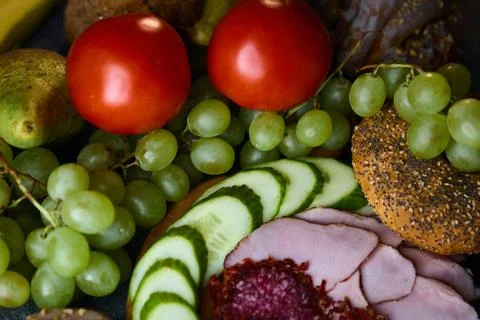 Culinary composition of ham salami tomatoes grapes and cinnamon buns 写真素材