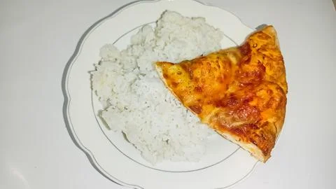 A culinary experiment: a slice of pizza on a plate of rice 스톡 사진
