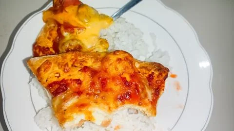 A culinary experiment: a slice of pizza on a plate of rice 스톡 사진