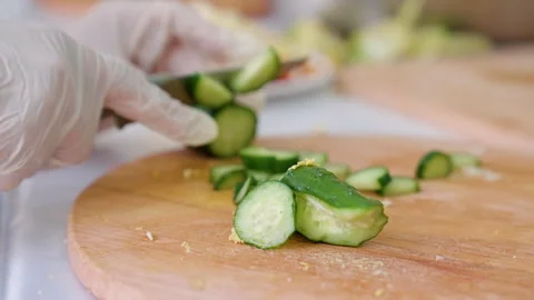 Culinary expert skillfully slicing fresh cucumbers on a wooden cutting board Stock Footage 318709921