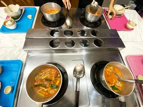 Culinary master class featuring multiple pots of soup on a stainless steel stove Stock-Fotos
