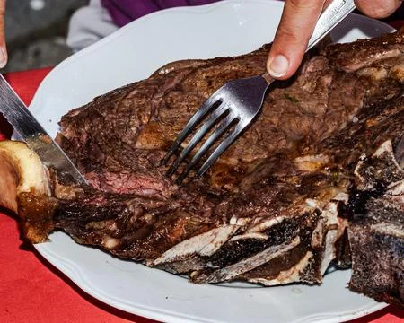 Culinary Mastery: Woman's Hands Slice into Succulent Barbecue Rib Steak wit.. Foto stock
