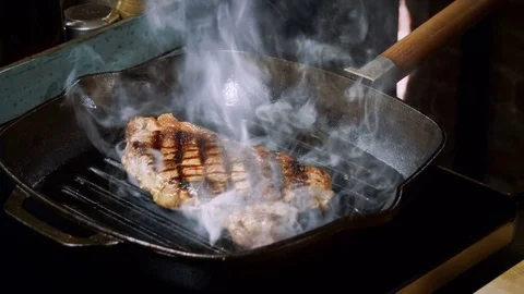 Culinary. One beef steak is being turned over and fried in a broiler pan. 4K Stock Footage 84255349