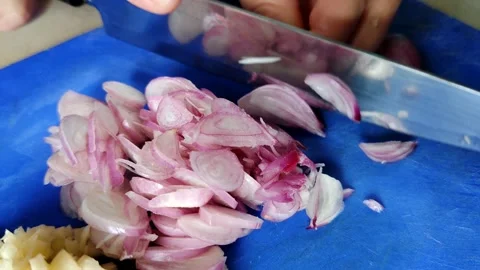 A culinary preparation scene featuring hands finely chopping onions and garlic Stock Footage 304065395