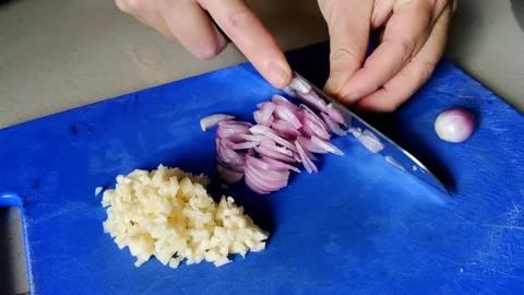 A culinary preparation scene featuring hands finely chopping onions and garlic Stock Footage 304065561
