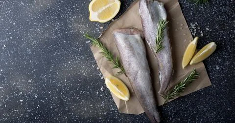Culinary presentation of uncooked hake with aromatic herbs, suited for gourmet Stock Photos