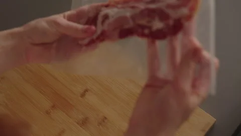 Culinary professional checking vacuum-sealed bacon package, maintaining food Stock Footage 312722213