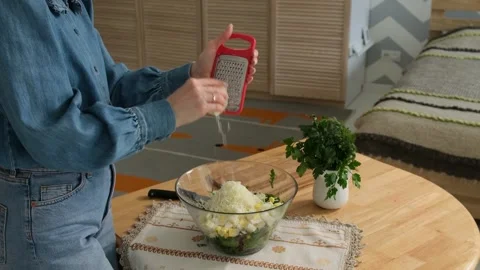 Culinary scene featuring a woman grating hard cheese with a hand grater into a Stock Footage 345048268