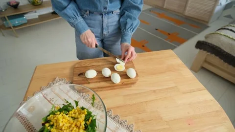 Culinary scene showing a woman's hands using a knife to slice boiled eggs on a Stock Footage 345048411