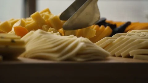 Culinary tongs pick up a square piece of cheese from an elegant cheese spread Video stock 99609965
