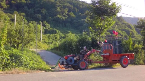 Cultivator engine connected to a water pump pumping water on a rural road in Sou Stock Footage 340579772