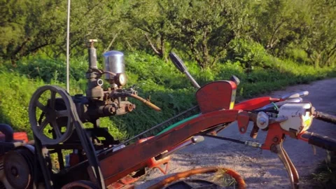Cultivator engine connected to a water pump pumping water on a rural road in Sou Stock Footage 340579773