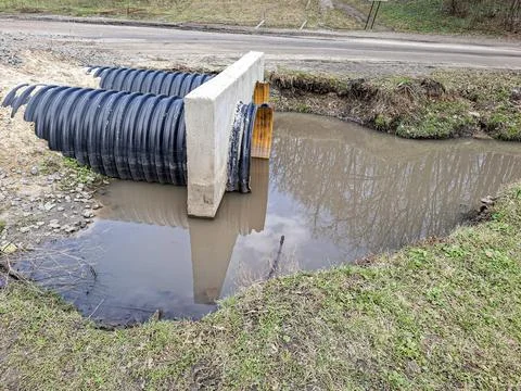 Culvert system under road with muddy water reflection and concrete headwall.. Stock-Fotos