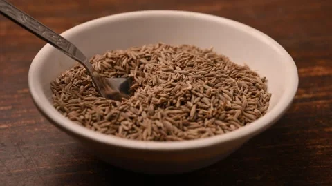 Cumin Seeds Being Scooped with Spoon from Bowl  Top View  Blur Background Video stock 334641432