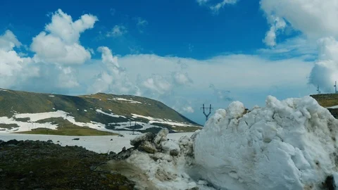 Cumulus clouds in blue sky above mountain covered with snow. View from side car 库存影片 92545876