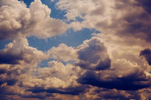 Cumulus clouds in blue sky in evening magenta light Stock Photos