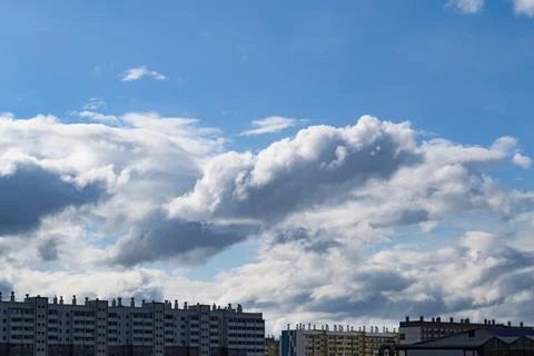 Cumulus clouds in the blue sky over multi-storey buildings Foto stock