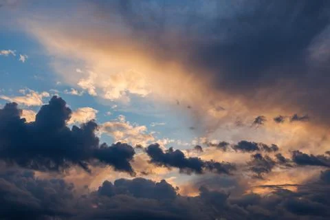 Cumulus clouds on evening sky backlit with sunset Stock Photos