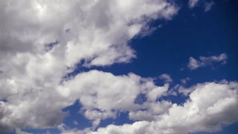 Cumulus clouds float across a clear blue sky Stock Footage 132932868