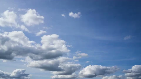 Cumulus clouds move from us across a bright blue sky Stock Footage 162358266