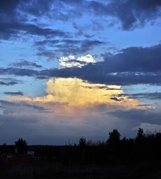 Cumulus clouds in the rays of the setting sun. Spring in the foothills of the Stock Photos